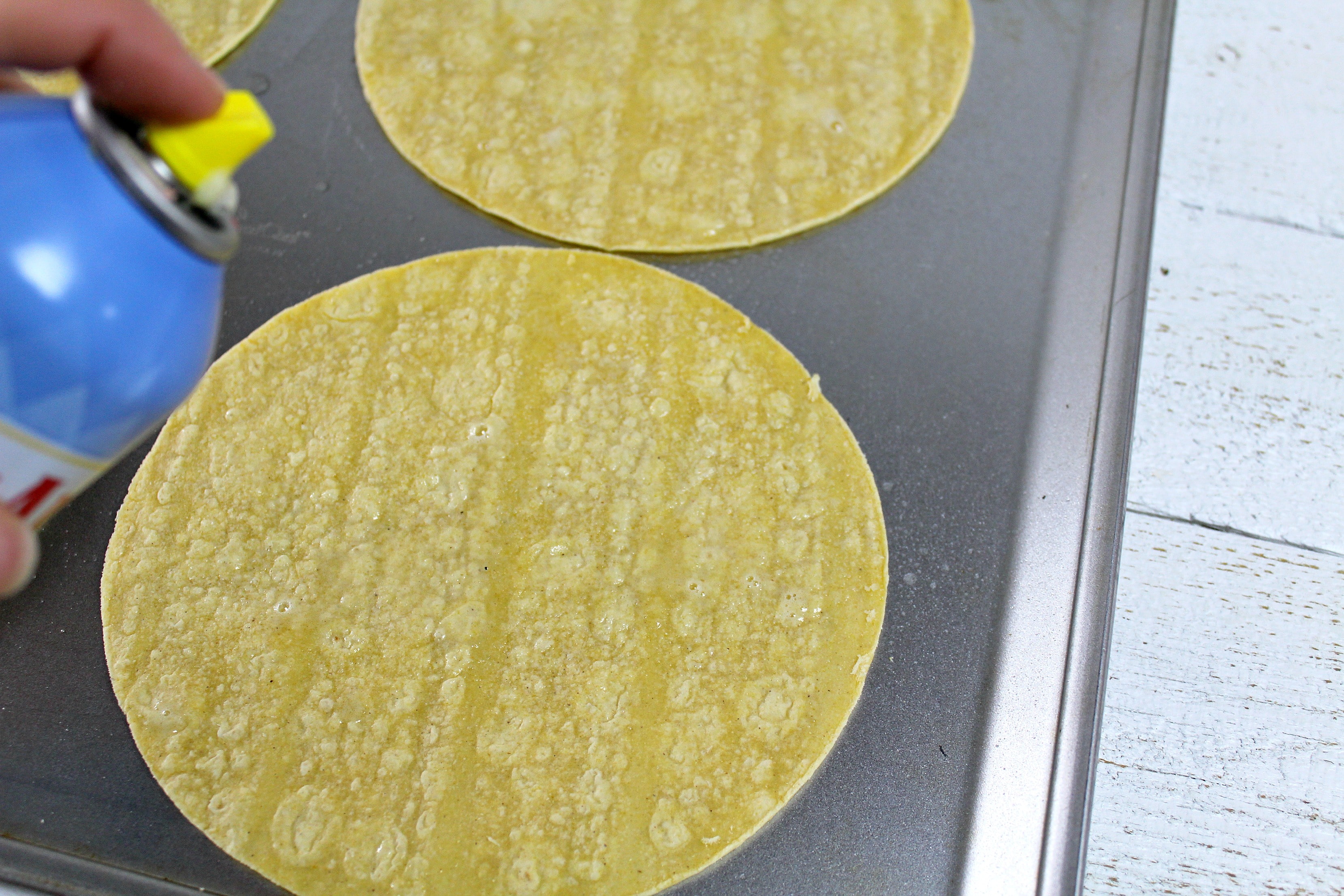 Use cooking spray on your corn tortillas, laying them flat across a baking sheet. 