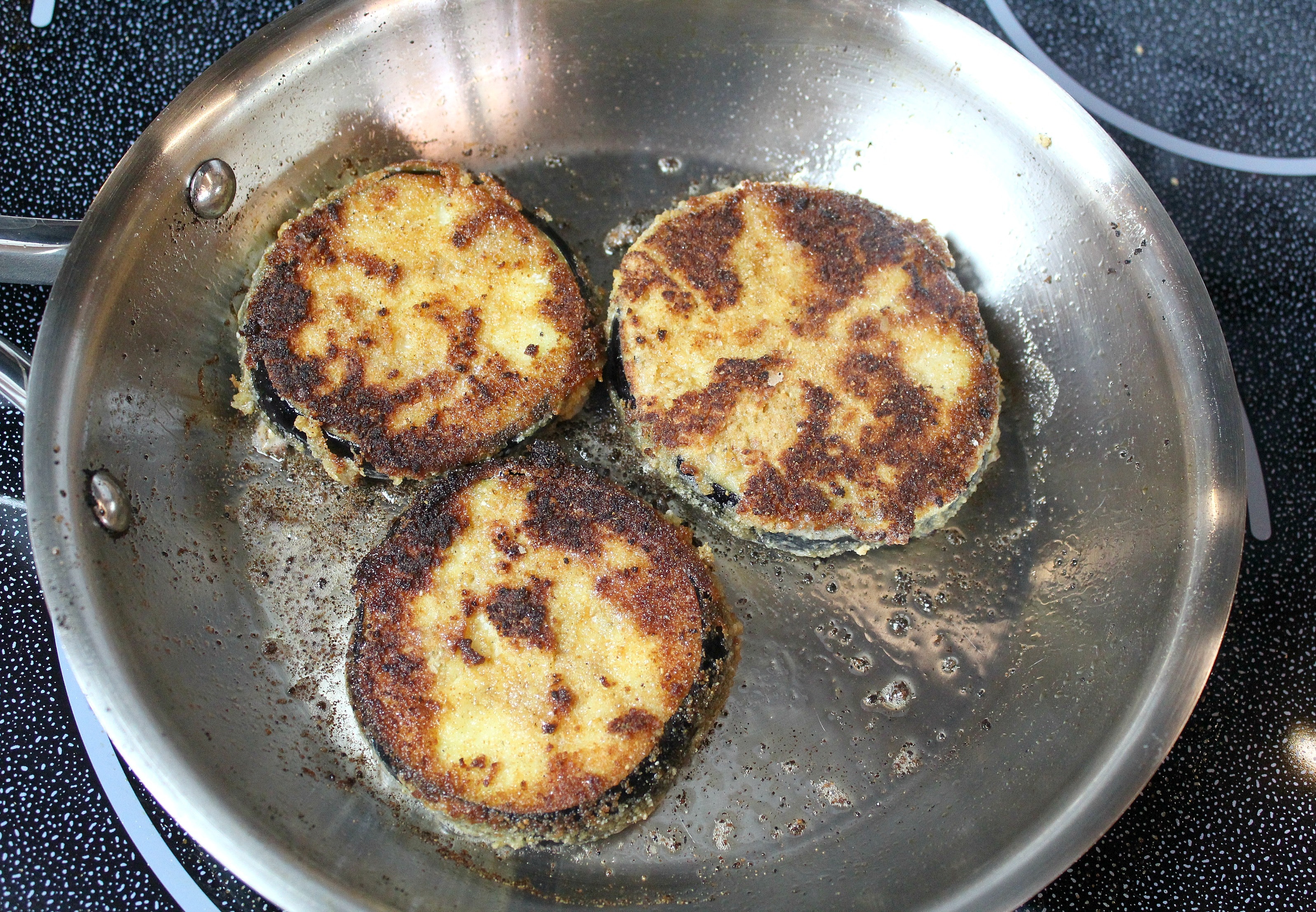 Place eggplant slices coated in breadcrumbs in oil and fry until golden brown, 