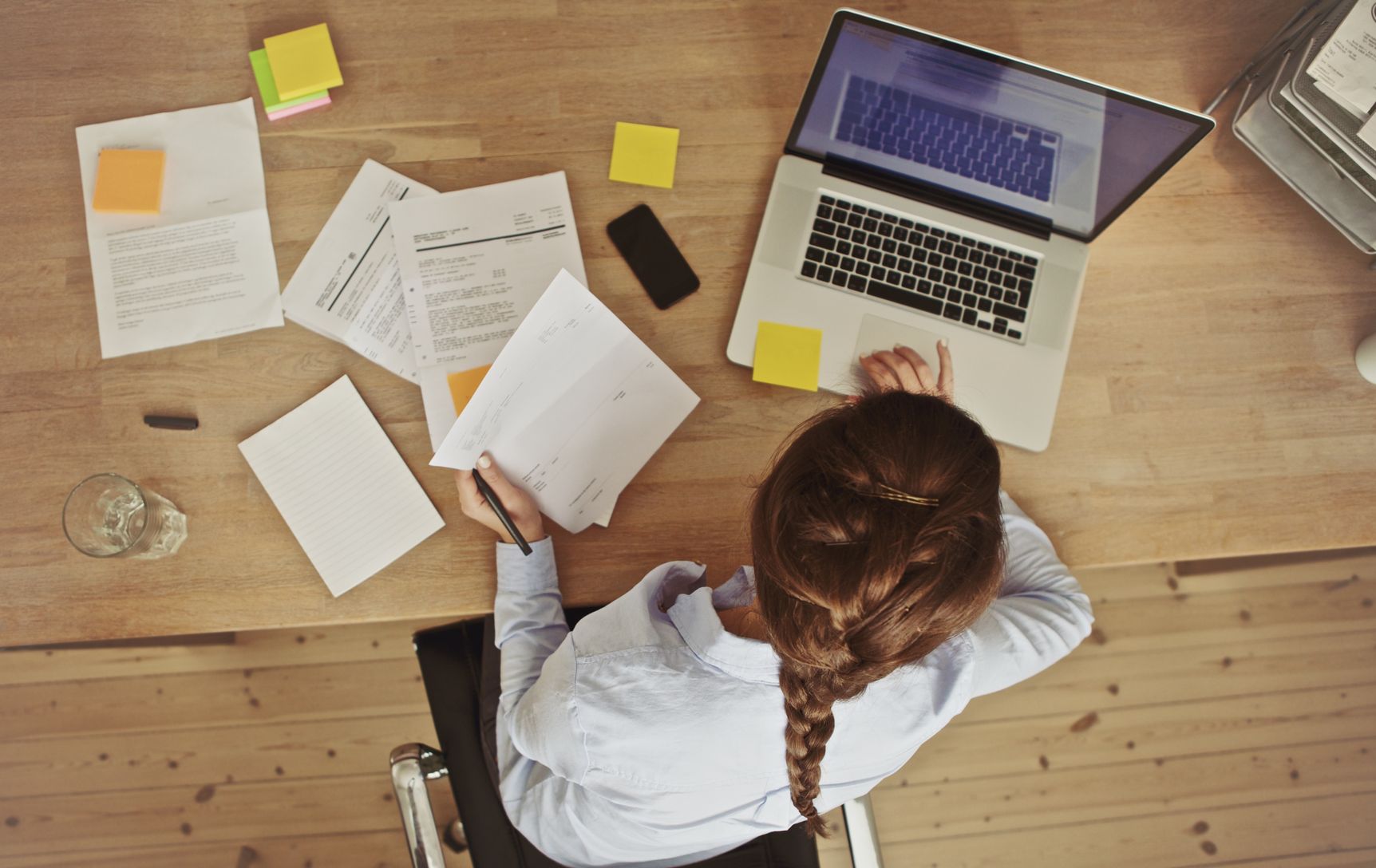 A woman organizing her finances with paperwork and her laptop. 