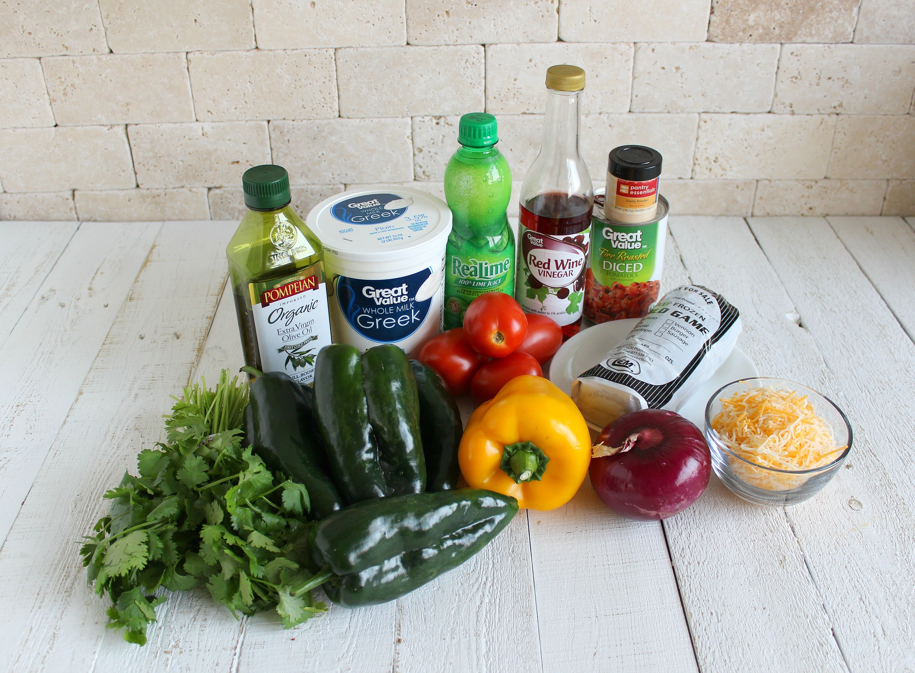 Assemble your ingredients: poblano peppers, ground meat, cheese, garlic powder, diced tomatoes, yellow bell pepper, red onion, cilantro, lime juice, olive oil, red wine vinegar and salt. 