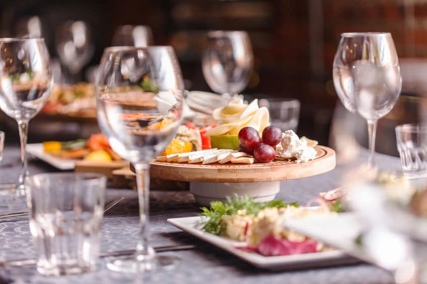 A fancy dining table set with shiny glassware, appetizers and utensils. 