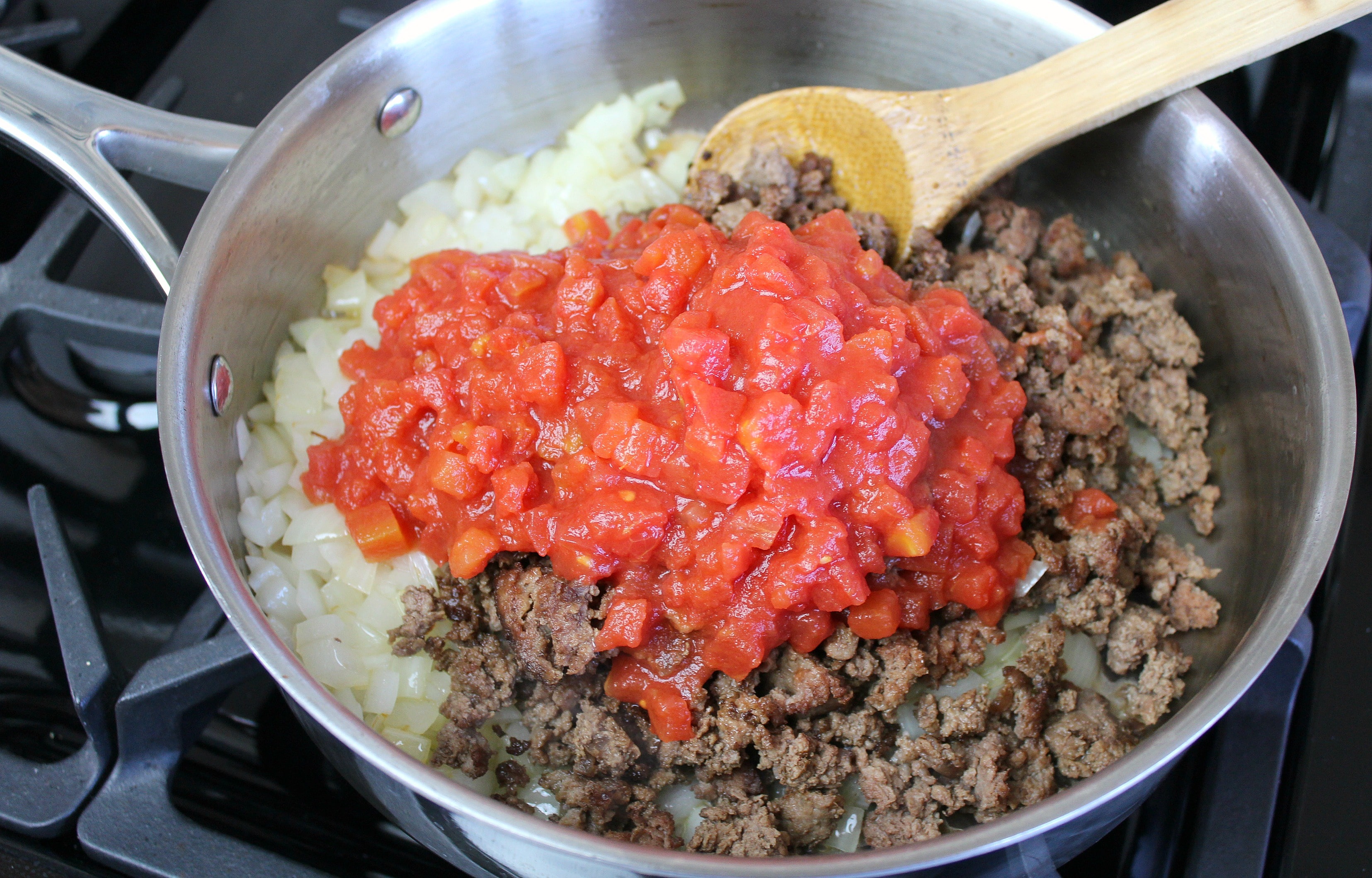 Add the crumbles and diced tomatoes to the onion mixture in the pan. 