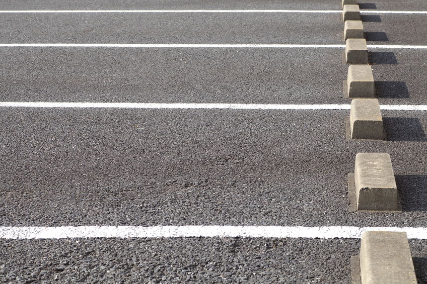 This parking lot has clear white lines and cement parking barriers. 