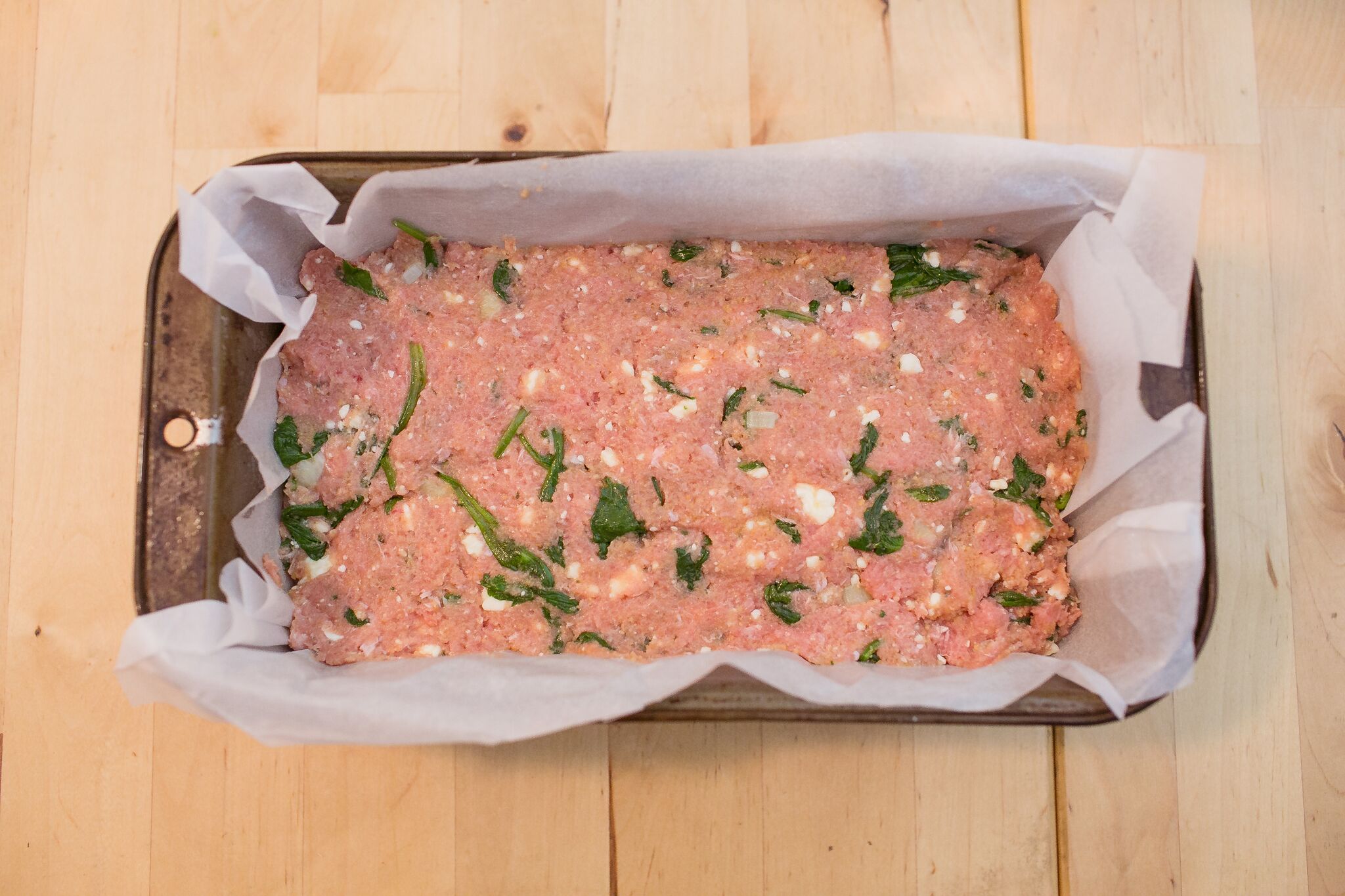 Add meat mixture to a loaf pan lined with parchment paper