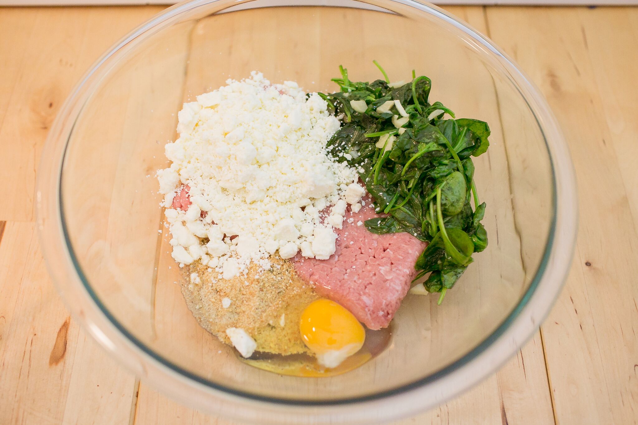 Combine meat, breadcrumbs, cheese, an egg, and spinach in a bowl