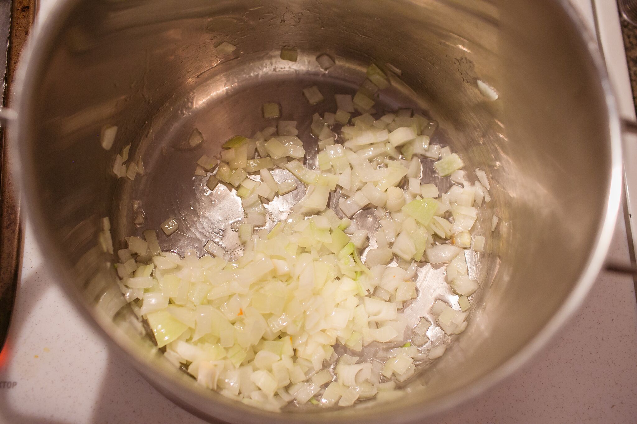 Add chopped yellow onions to a large soup pot and sauté until lightly golden. 