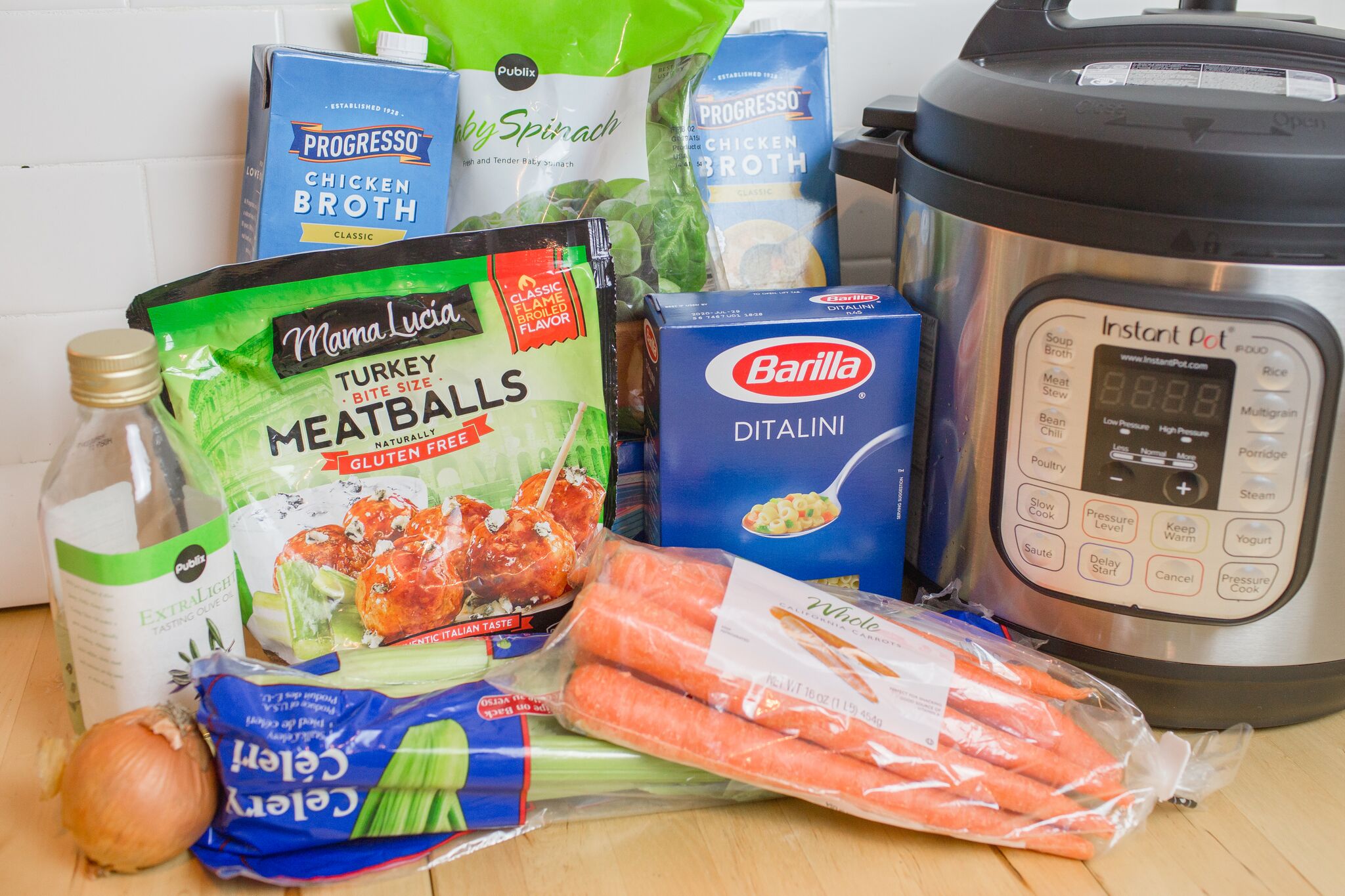 Assemble your ingredients for the Italian wedding soup: carrots, celery, yellow onion, turkey meatballs, ditalini pasta, chicken broth, spinach and olive oil. 