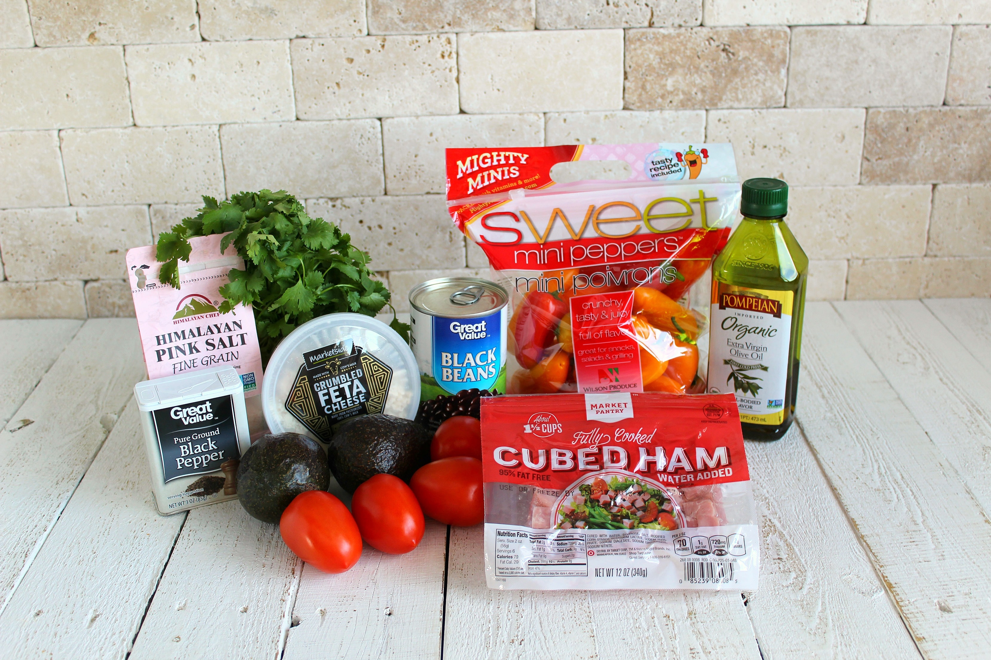 Assemble your ingredients for the ham and black bean salad: bell peppers, tomatoes, cilantro, feta, ham, black beans, olive oil, salt, pepper and avocados.