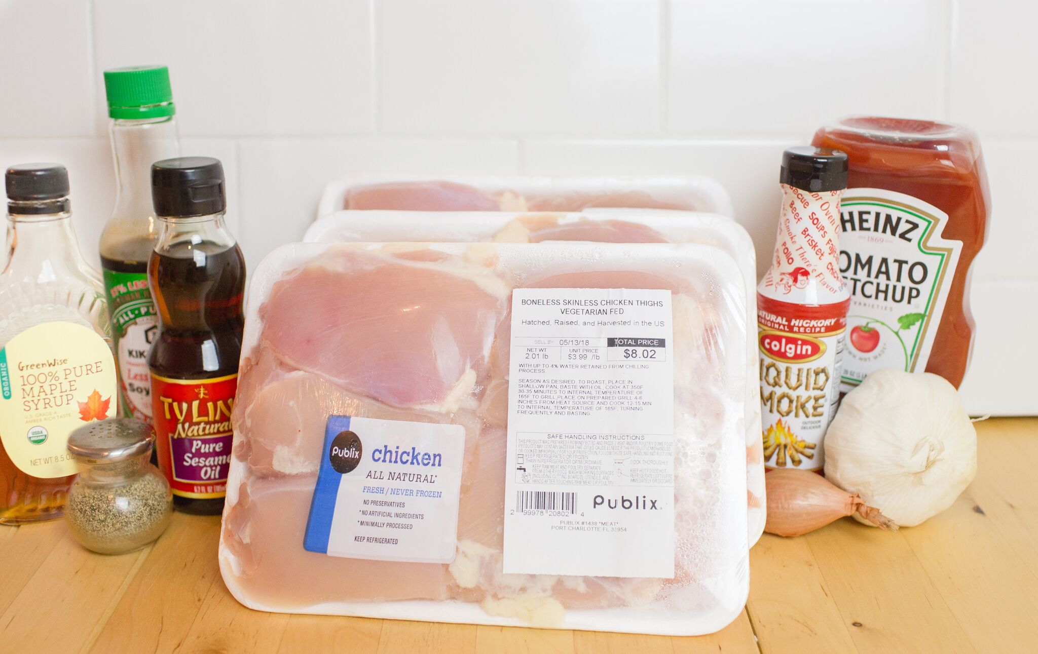 Assemble your ingredients for the smokey maple chicken: boneless, skinless chicken thighs, garlic, shallot, sesame oil, soy sauce, black pepper, liquid smoke, ketchup and maple syrup.